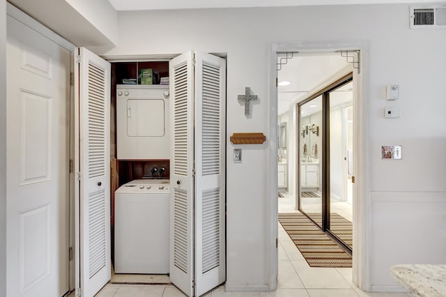 clothes washing area featuring stacked washer and clothes dryer and light tile patterned floors