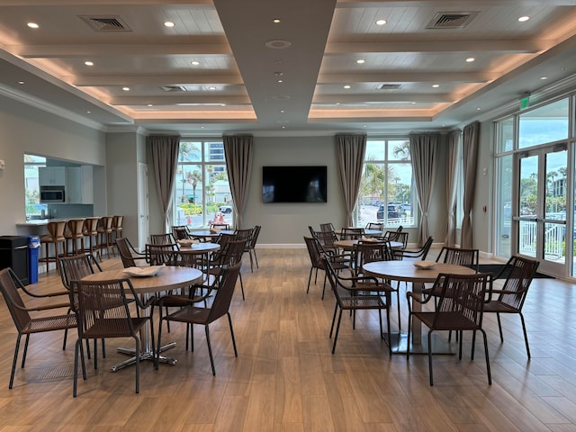 dining area featuring light wood-type flooring, a raised ceiling, and plenty of natural light