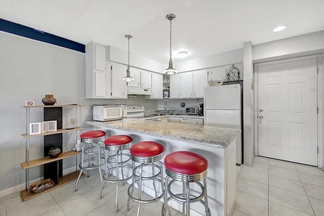 kitchen featuring kitchen peninsula, a breakfast bar, white cabinetry, pendant lighting, and white appliances