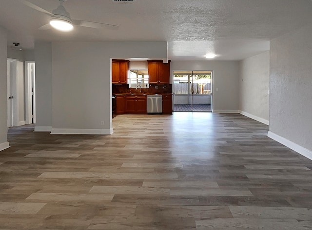 unfurnished living room with ceiling fan, a textured ceiling, wood-type flooring, and sink