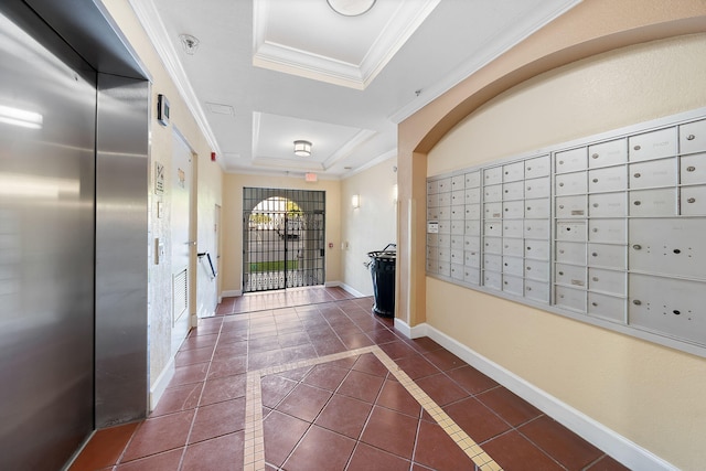 interior space with dark tile patterned floors, ornamental molding, a mail area, a tray ceiling, and elevator