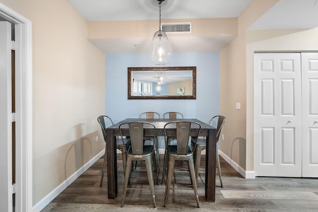 dining area with wood-type flooring and a textured ceiling