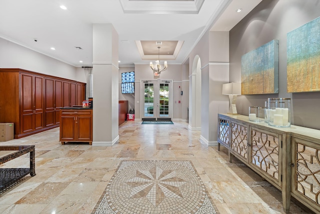 interior space with ornamental molding, an inviting chandelier, and a raised ceiling