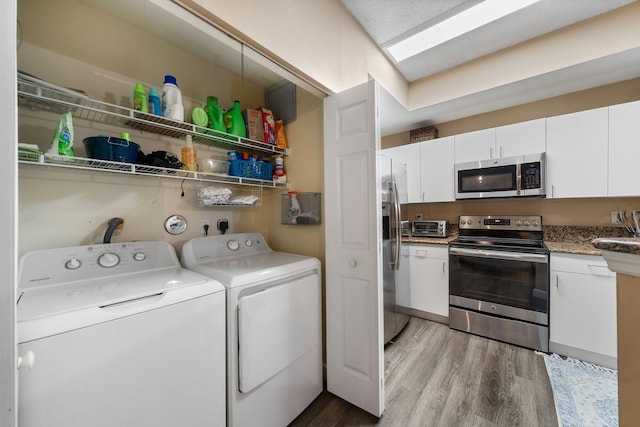 laundry room featuring washing machine and clothes dryer and light hardwood / wood-style flooring