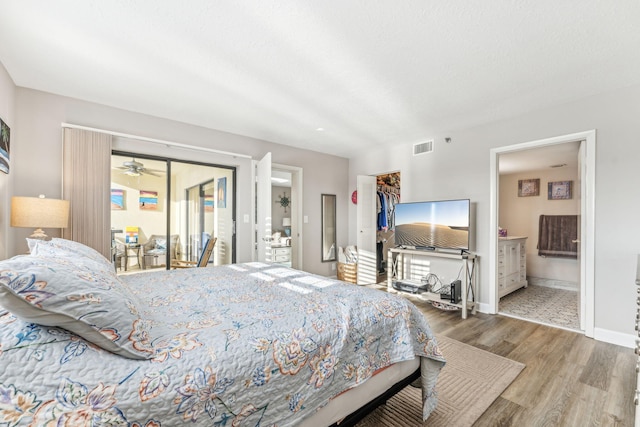 bedroom with hardwood / wood-style floors, a walk in closet, ensuite bathroom, and a closet