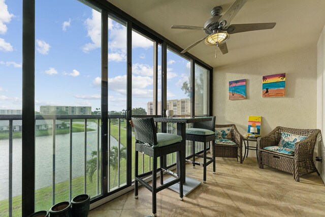 sunroom / solarium featuring a water view and ceiling fan