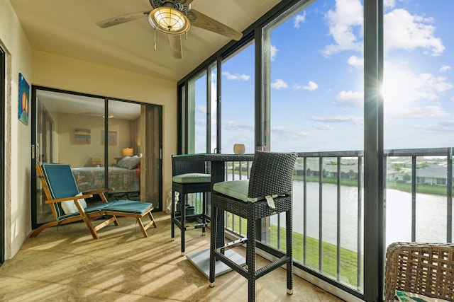 sunroom / solarium with a water view and ceiling fan