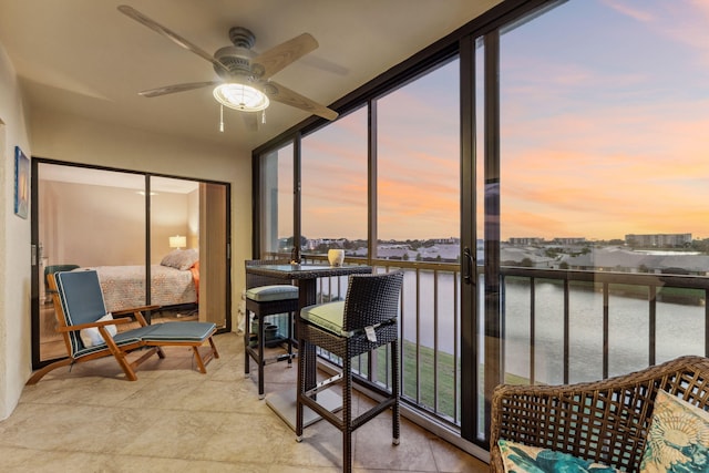 sunroom with a water view and ceiling fan