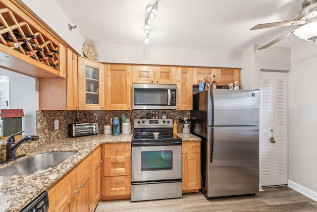 kitchen featuring sink, appliances with stainless steel finishes, a textured ceiling, and light wood-type flooring