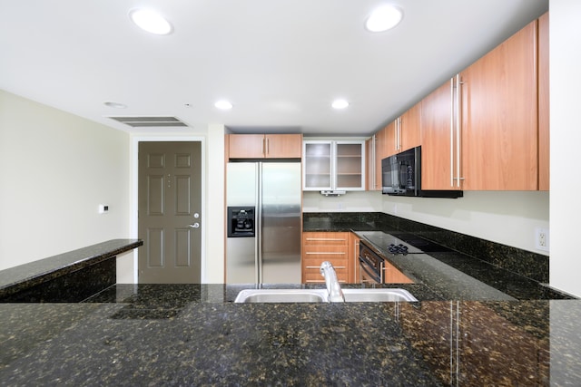 kitchen with dark stone countertops, sink, and stainless steel fridge with ice dispenser