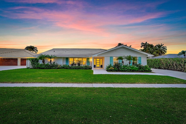 ranch-style home with a yard, a garage, and a porch