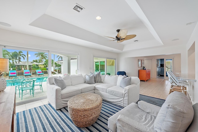 tiled living room featuring ceiling fan and a raised ceiling