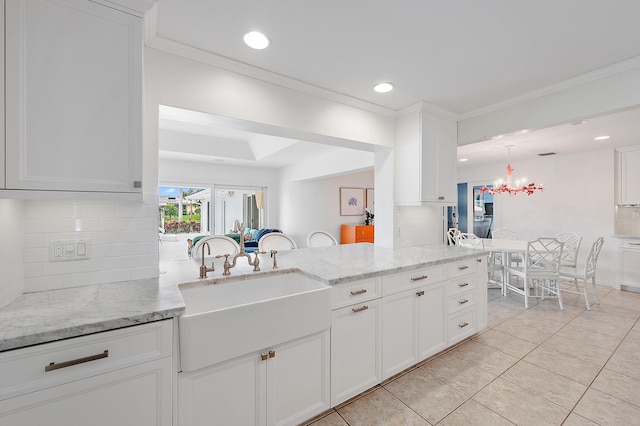 kitchen with tasteful backsplash, light stone countertops, sink, white cabinets, and light tile patterned floors