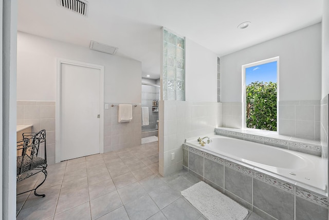 bathroom featuring shower with separate bathtub, tile walls, and tile patterned flooring