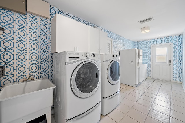 clothes washing area featuring cabinets, sink, washer and clothes dryer, and light tile patterned floors