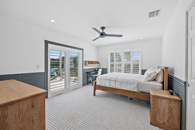 carpeted bedroom featuring wood walls, access to exterior, multiple windows, and ceiling fan