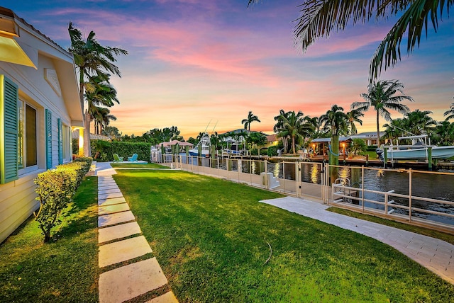 yard at dusk with a water view and a dock