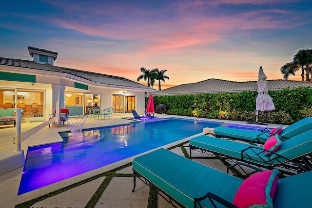 pool at dusk with a patio area