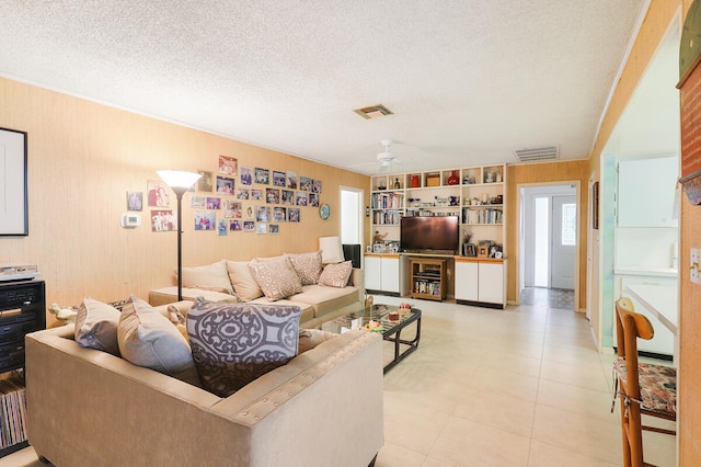 living room featuring ceiling fan, built in features, and a textured ceiling