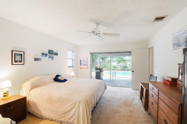 bedroom with a textured ceiling, access to exterior, light colored carpet, and ceiling fan