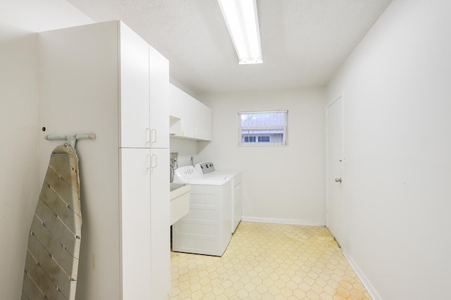 laundry room featuring a textured ceiling, washing machine and dryer, and cabinets