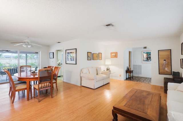 living room featuring light hardwood / wood-style floors, a textured ceiling, and ceiling fan