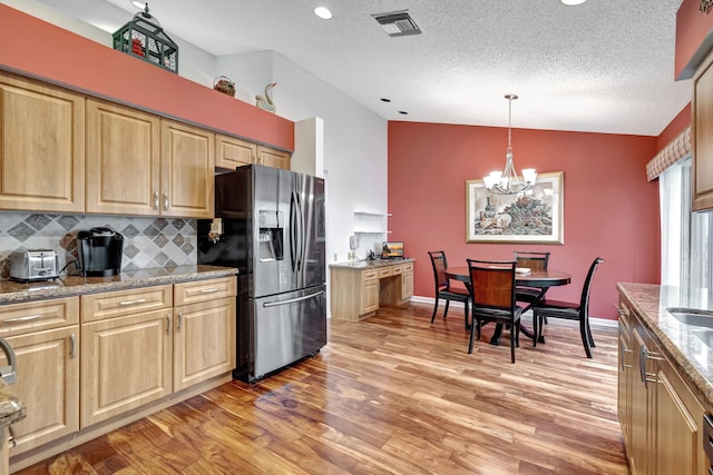 kitchen featuring decorative backsplash, hanging light fixtures, wood-type flooring, stainless steel fridge with ice dispenser, and light stone counters