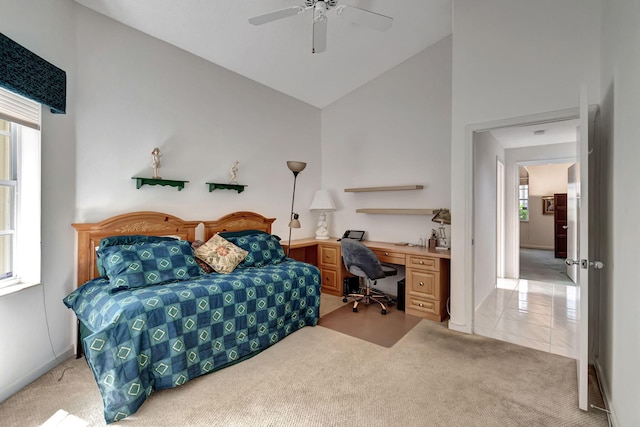 bedroom featuring built in desk, light colored carpet, high vaulted ceiling, and ceiling fan