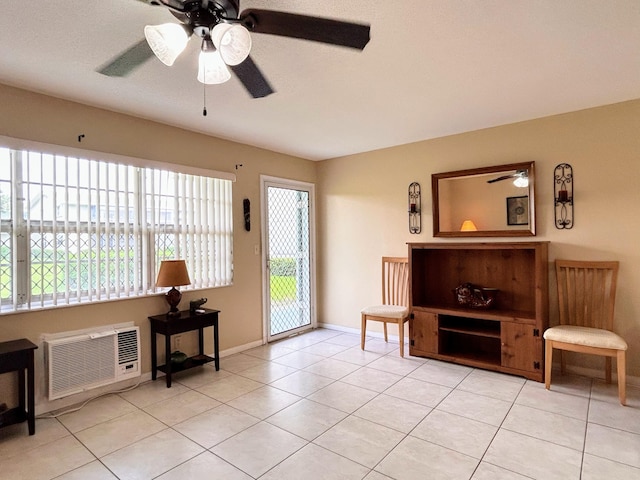 living area with a wall unit AC, ceiling fan, and light tile patterned floors