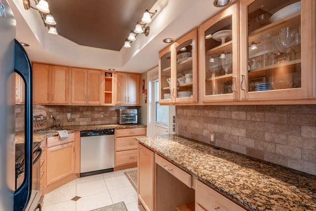 kitchen featuring dishwasher, tasteful backsplash, dark stone countertops, refrigerator, and a tray ceiling