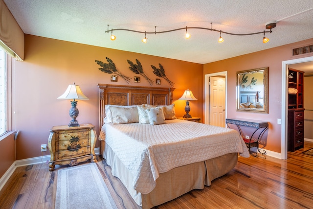 bedroom with multiple windows, wood-type flooring, and a textured ceiling