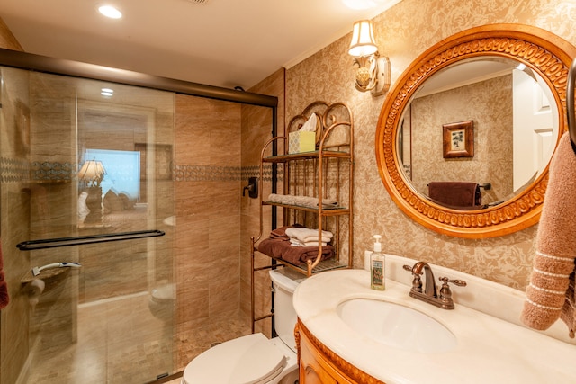 bathroom with ornamental molding, vanity, toilet, and a shower with shower door