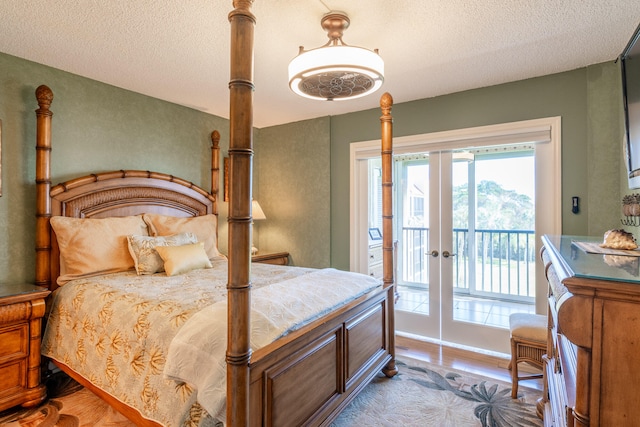 bedroom with access to exterior, french doors, a textured ceiling, and hardwood / wood-style flooring