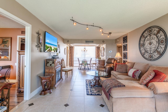 living room with light tile patterned flooring, a chandelier, and a textured ceiling