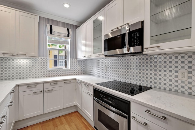 kitchen featuring stainless steel appliances, light stone counters, light hardwood / wood-style flooring, decorative backsplash, and white cabinets