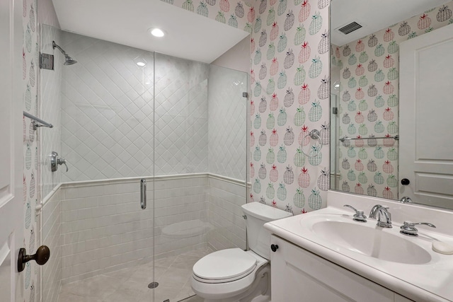 bathroom featuring vanity, toilet, walk in shower, and tile walls