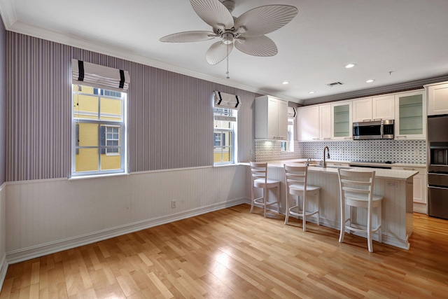 kitchen with a breakfast bar, light hardwood / wood-style flooring, white cabinetry, and crown molding