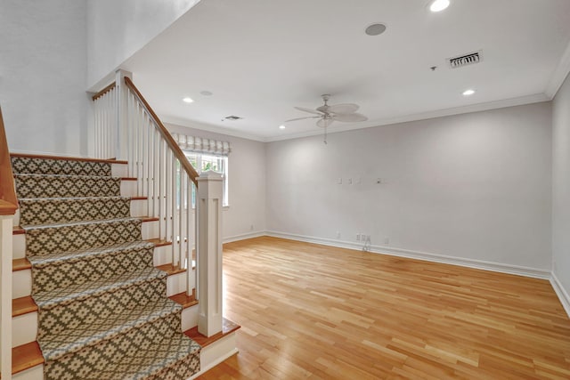 staircase featuring crown molding, ceiling fan, and wood-type flooring