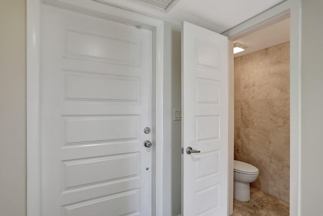 bathroom featuring tile walls, toilet, and tile patterned floors