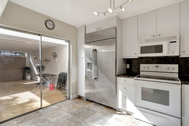 kitchen featuring dark stone countertops, white cabinets, backsplash, and white appliances