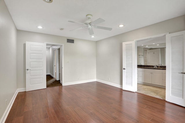 unfurnished bedroom featuring wood-type flooring, sink, ensuite bathroom, and ceiling fan