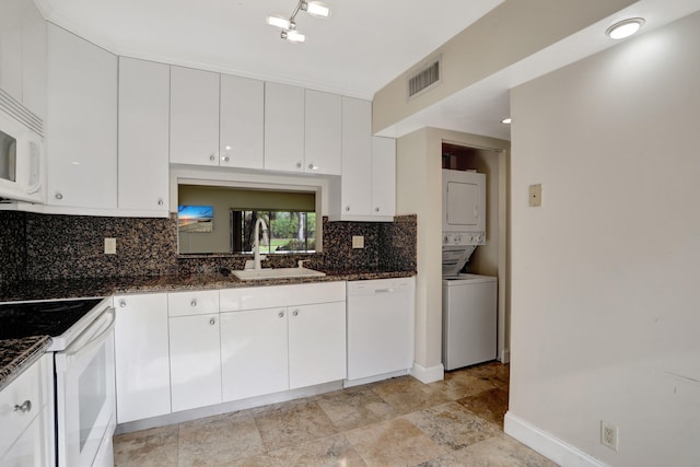 kitchen featuring sink, white cabinetry, white appliances, and stacked washing maching and dryer