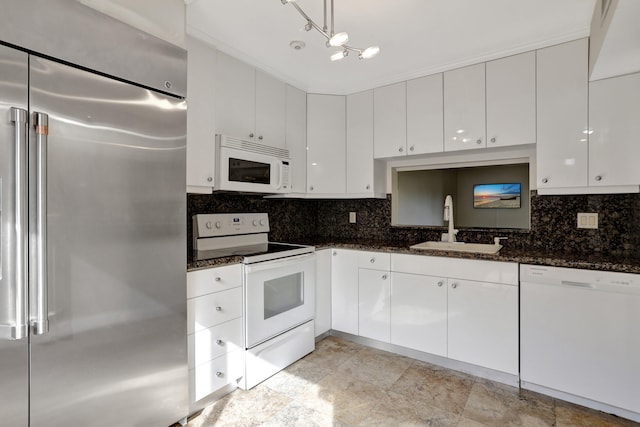 kitchen featuring decorative backsplash, dark stone countertops, white appliances, sink, and white cabinetry