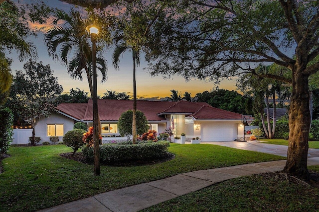 mediterranean / spanish-style home with a garage and a lawn