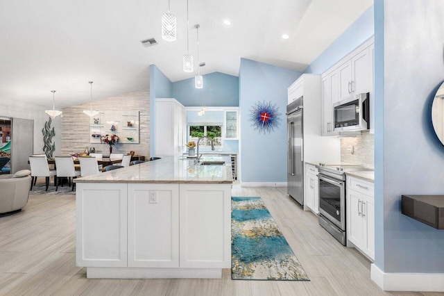 kitchen featuring a center island with sink, hanging light fixtures, appliances with stainless steel finishes, white cabinetry, and light stone countertops