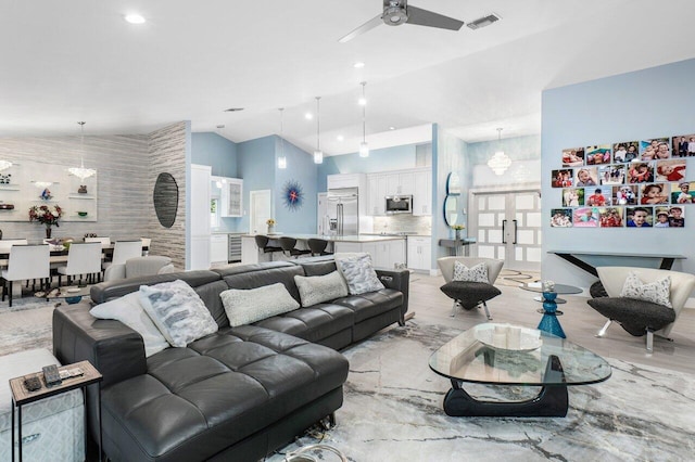 living room featuring light hardwood / wood-style floors, high vaulted ceiling, and ceiling fan with notable chandelier