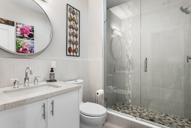 bathroom featuring a shower with door, vanity, and toilet