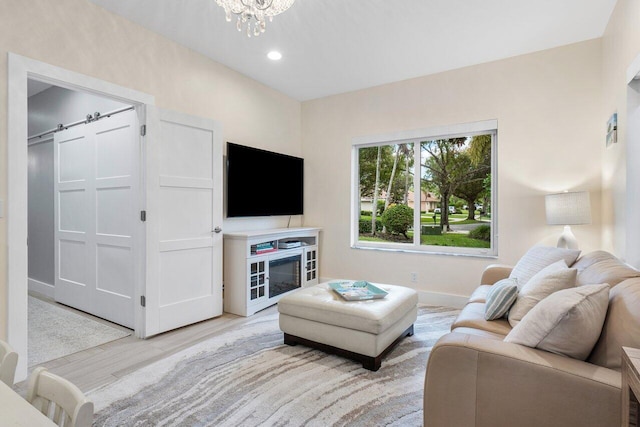 living room featuring a chandelier, a barn door, and light hardwood / wood-style flooring