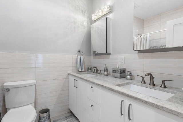 bathroom with vanity, toilet, and tile walls