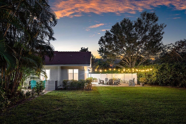 yard at dusk with central AC and a patio